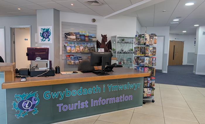 Reception desk inside Llandudno Tourist Information Centre with visitor guides, maps and local gifts on display.